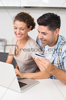 Happy couple using laptop together to shop online