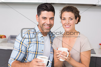 Happy couple having coffee smiling at camera