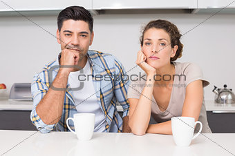 Fed up couple having coffee looking at camera