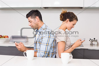 Couple sitting back to back texting