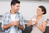 Attractive couple sitting having coffee together and laughing