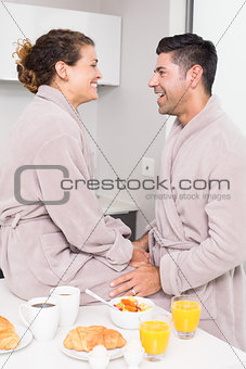 Happy couple in bathrobes having breakfast together