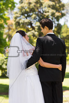 Rear view of newlywed with arms around in park
