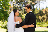 Newlywed couple with arms around in park
