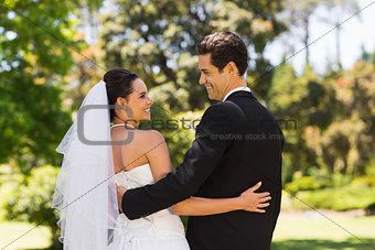 Newlywed couple with arms around in park