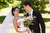 Romantic newlywed couple with bouquet in park
