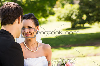 Romantic newlywed couple looking at each other in park