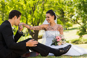 Groom kissing his bride's hand at park
