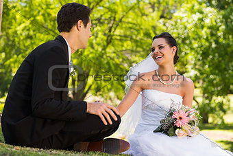 Happy newlywed couple sitting in park