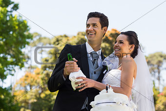 Newlywed couple with champagne bottle at park
