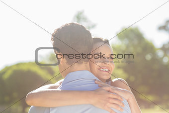 Loving and happy woman embracing man at park