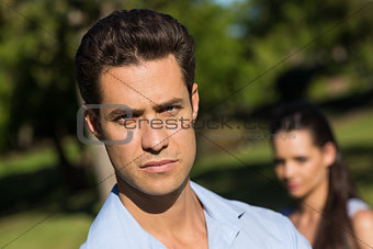Man with blurred woman in background outdoors