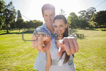 Young couple pointing finger to the camera at park