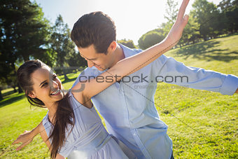 Happy young couple with arms outstretched at park
