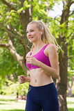 Healthy and beautiful woman in sports bra jogging in park
