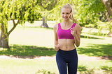 Healthy and beautiful woman in sports bra jogging in park