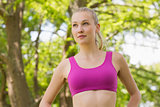 Healthy and beautiful woman in sports bra against trees in park