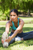 Healthy and beautiful woman stretching hands to leg in park