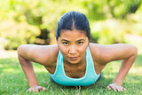 Portrait of a healthy woman doing push ups in park