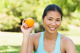 Healthy woman holding orange in park