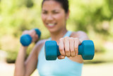 Blurred woman exercising with dumbbells in park