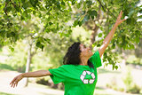 Woman in green recycling t-shirt touching leaves at park