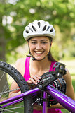Happy young woman wearing helmet with bicycle