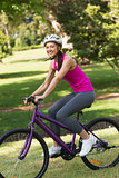 Fit woman with helmet riding bicycle at park