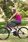 Fit young woman with helmet riding bicycle at park