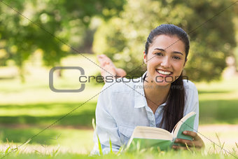 Portrait of a smiling woman reading book in park