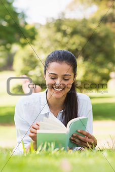 Smiling woman reading a book in park