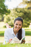 Smiling young woman reading a book in park