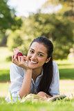 Smiling young woman reading a book in park