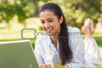 Smiling young woman using laptop in park