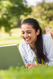 Smiling woman using laptop in park