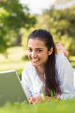 Portrait of smiling woman using laptop in park