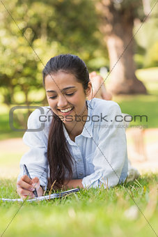 Smiling woman with book and pen in park
