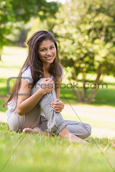 Portrait of a smiling woman sitting on grass in park