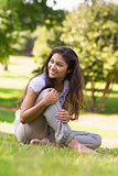 Full length of a smiling woman sitting on grass in park
