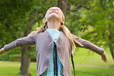 Girl with arms outstretched looking upwards at park