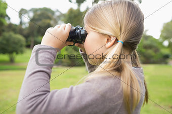Girl looking through binoculars at park
