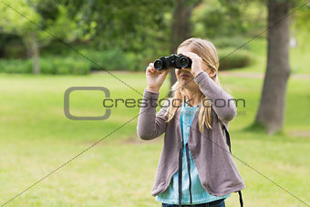 Young girl looking through binoculars at park