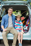 Portrait of father and son sitting in car trunk