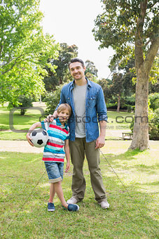 Smiling father and son with ball at park