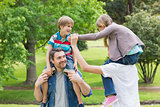 Parents carrying kids on shoulders at park