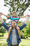 Father carrying boy on shoulders in park
