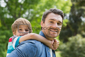 Father carrying young boy on back at park