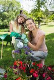 Portrait of mother with daughter watering plants