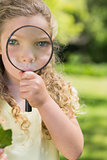 Cute girl looking through magnifying glass at park