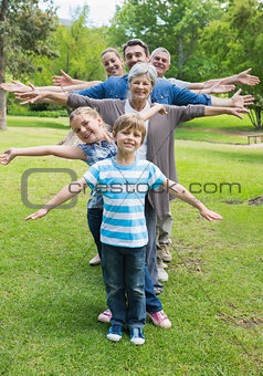 Extended family standing in row with arms outstretched at park